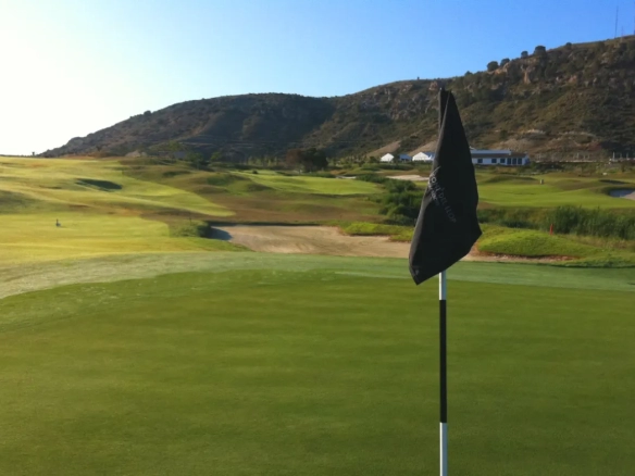 Scenic golf course in Spain with lush green fairways, sand bunkers, and mountains in the background - perfect for golf breaks in Spain