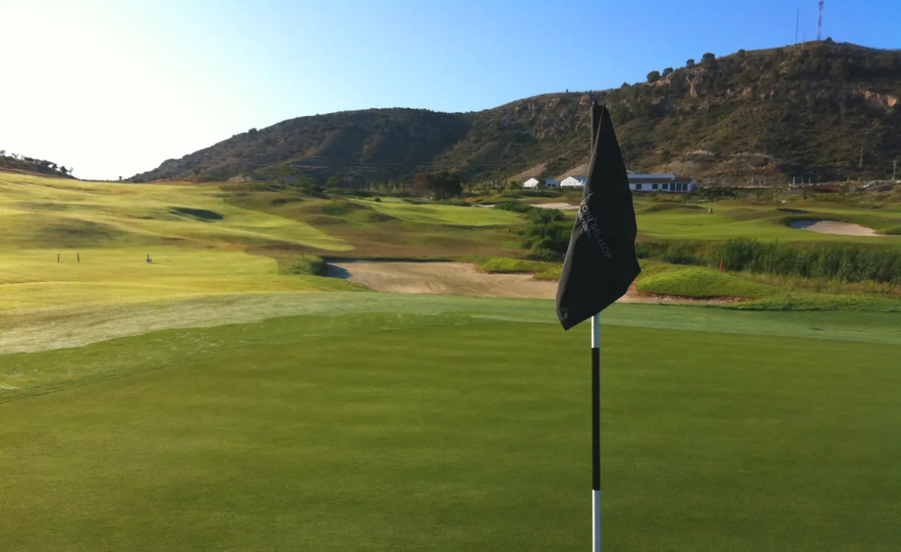 Scenic golf course in Spain with lush green fairways, sand bunkers, and mountains in the background - perfect for golf breaks in Spain
